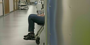 Eine Person sitzt in einem Rollstuhl in einem Krankenhausflur