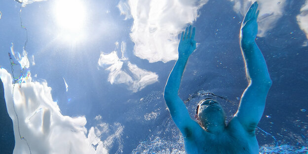 Mann schwimmt durch das Wasser eines Freibads