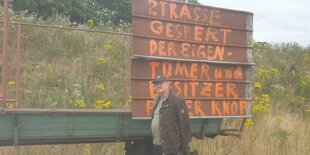 Bauer Knop vor einem selbstgemalten Schild auf einem Anhänger