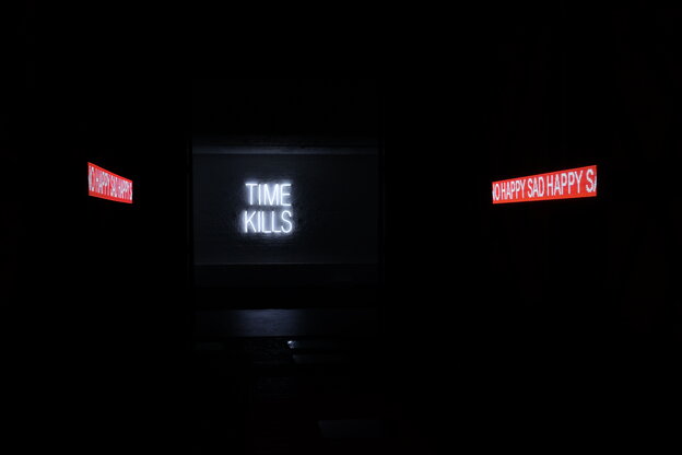 Eine Drei-Kanalvideoinstallation im abgedunkelten Raum. Rechts und links sind Weiß auf Rot zu lesen "No Happy Sad", in der Mitte ist Weiß auf Schwarz zu lesen "Time Kills"