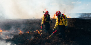 Zwei Feuerwehrleute legen mit Hilfe von Gießinstrumenten ein kontrolliertes Gegenfeuer