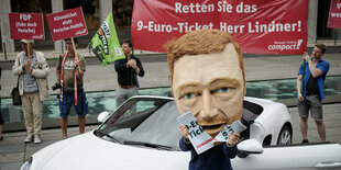 Eine Lindner-Figur und mehrere Personen bei einer Protestaktion.