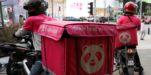 Pinkfarbener Transporrtbehälter des Panda-Lieferdienstes,2 Fahrer von hinten aufgenommen