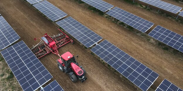 Ein Traktor zwischen Solarpannels.