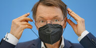 Karl Lauterbach (SPD), Bundesminister für Gesundheit, zieht sich eine Maske an.