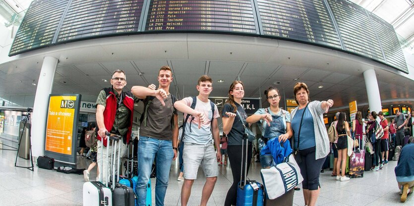 Passagiere am Flughafen zeigen den Daumen nach unten.