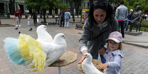 Eine Frau mit Kind füttert Vögel.