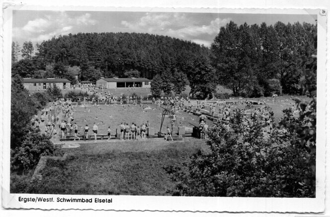 Schwarz-weiss Foto vom Elsebad in den 50er Jahren, viele Badegäste stehen um das Becken und beobachten die SchwimmerInnen