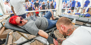 Verein first: Ein weiblicher Schalke-Fan lässt sich ein Schalke-Tattoo stechen.