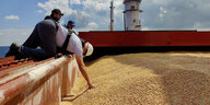 Ein Schiffsmitarbeiter greift in das geladene Getreide an bord der Razoni