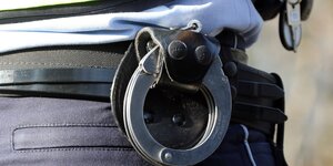 Handschellen eines Polizisten sind an einen Gürtel fixiert