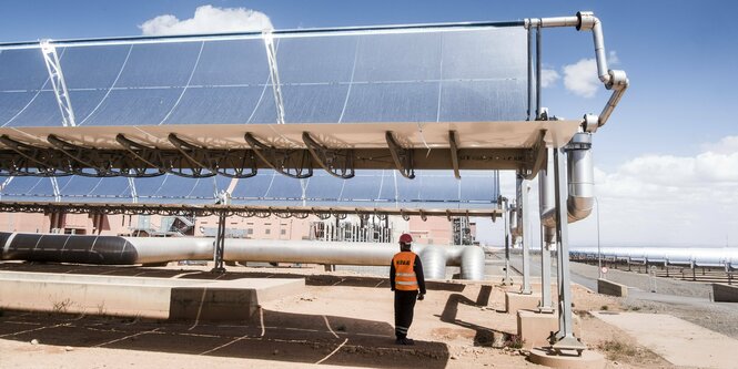 Ein mann steht unter einem großen Solarpanel in der Wüste