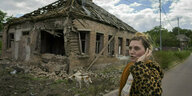 Eine Frau steht vor einem beschädigten Haus