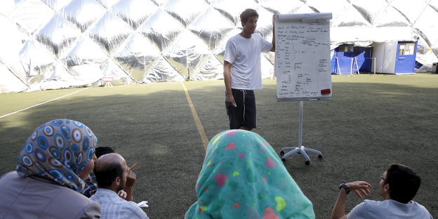 Ein Freiwilliger unterrichtet Asylsuchende in Moabit in Deutsch