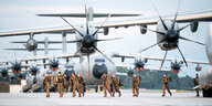 Soldaten in heller Flecktarn-Kleidung vor der Tragfläche eines Transportflugzeugs der Bundeswehr