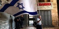 EIn Mann schwenkt eine große Israel Flagge