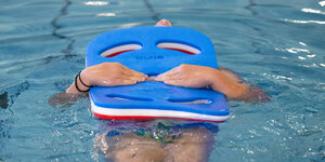 Ein Mädchen lernt schwimmen mit einem Schwimmbrett
