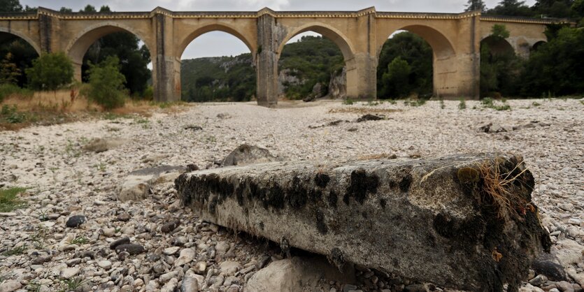 ausgetrocknetes Flussbett, im Hintergrund eine Brück