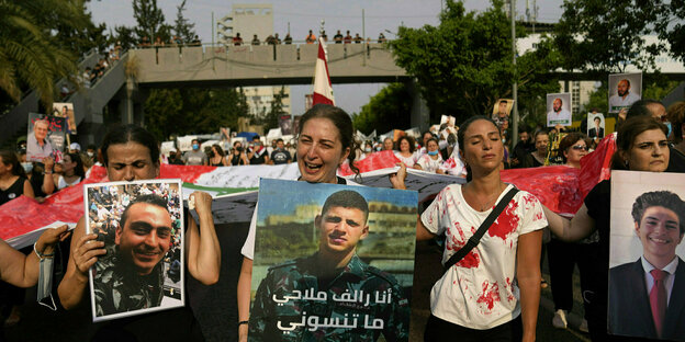 Eine Menschenmasse halten Portraits der Opfer und libaneische Flaggen