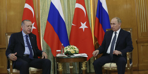 Recep Tayyip erdogan und Wladimir Putin sitzen auf Stühlen vor türkischen und russischen Flaggen