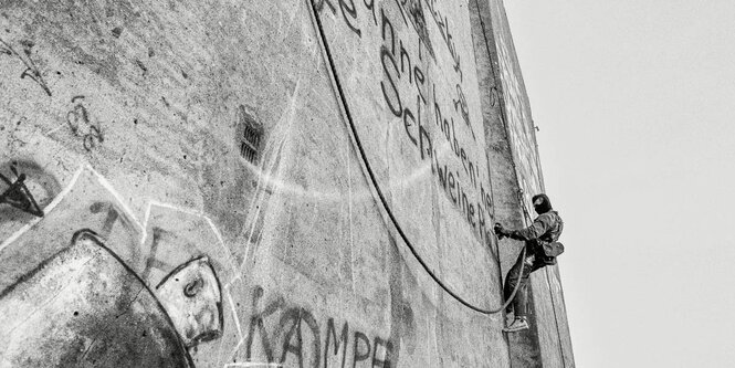 Spüher seilt sich von Hausfassade ab, schwarzweiß.