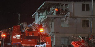 Ein beschädigtes Haus, davor ein Löschzug der Feuerwehr.