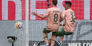 Zwei Bremer schauen auf den Ball im eigenen Tor