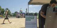 Klimaschützer mit Info-Schild, eine Passantin und ein Eis-Verkäufer vor dem Kapitol in Washington D.C..