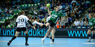 Handballspiel: Eine Frau wirft den Ball, von einer Gegenspielerin bedrängt