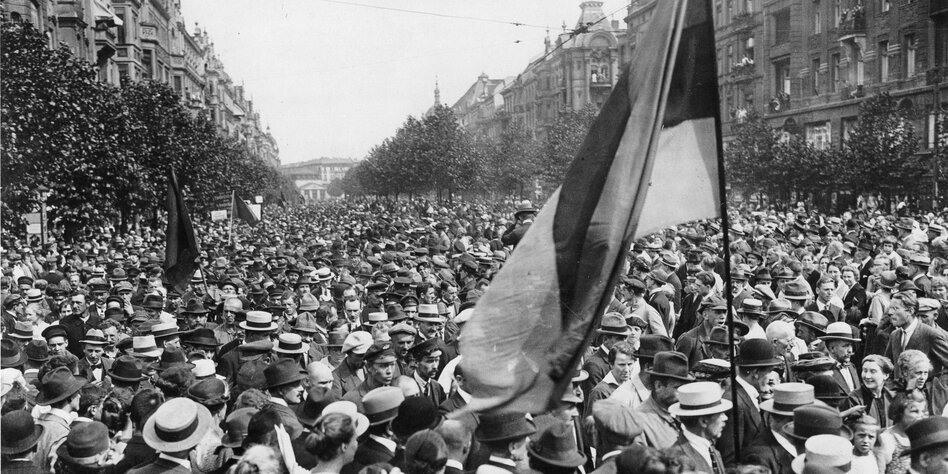 Eine Schwarzweißaufnahme einer großen Menschenmenge mit einer schwarz-rot-goldenen Flagge.