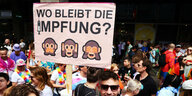 Ein Teilnehmer des CSD Berlin 2022 hält ein Plakat in die Höhe, auf dem gefragt wird, wann die Affenpocken-Impfung kommt.