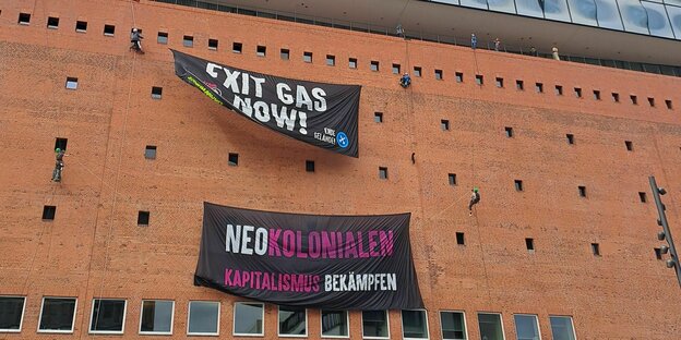 Zwei Banner hängen an der Fassade der Elbphilharmonie: "Exit Gas Now" und "Neokolonialen Kapitalismus überwinden".