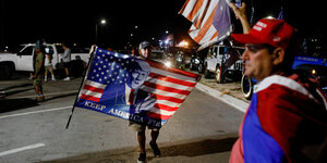 Männer mit amerikanischen und Trump-Flaggen in der Nacht auf der Straße