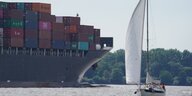 Ein Segelboot fährt an einem Containerschiff auf der Elbe vorbei