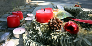 Rote Trauerkerzen und Teelichte liegen auf einer Straße