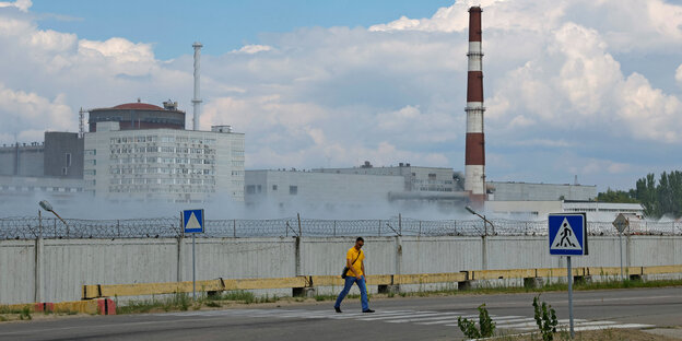 Ein Mann mit gelbem Shirt geht vor dem Atomkraftwerk Saporischschja auf einem Zebrastreifen