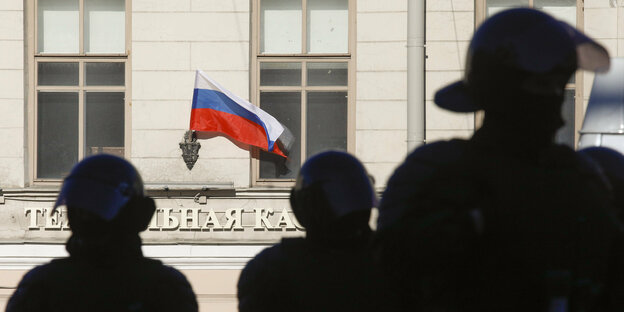 Schatten von Polizisten, im Hintergrund eine Russland-Flagge.