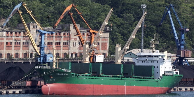 Ein Frachtschiff liegt in einem Hafen, mit mehreren Kränen