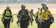 Eine Gruppe von Feuerwehrmännern und Feuerwehrfrauen in Schutzmontur nach einem Einsatz