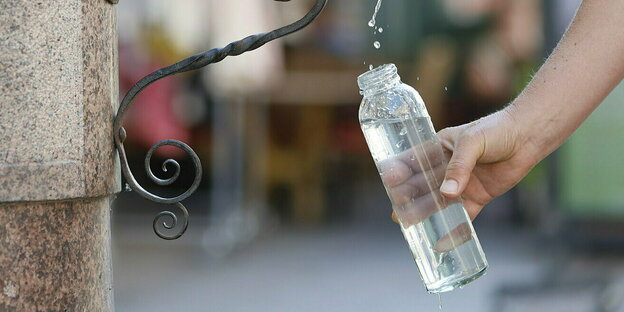 Eine Plastikflasche wird an einem Trinkbrunnen mit Wasser gefüllt