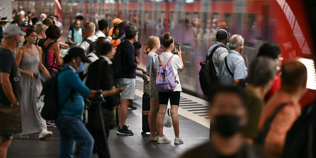 Menschen stehen auf einem Bahnsteig.