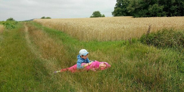 Ein Mädchen in rosa Kleidung und ein Junge spielen vor einem Weizenfeld