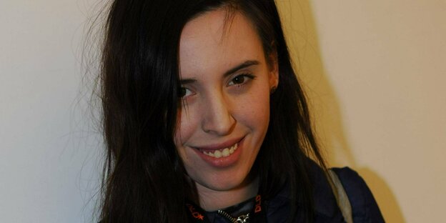 eine junge Frau mit lagngem dunklem Haar lächelt