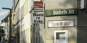 Ein Straßenzug, im Vordergrund eine Kneipe mit Schild: "Trinkhalle" und "Hartz IV-Ecke"