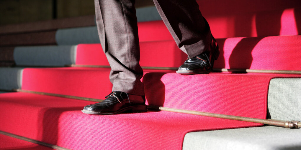 Eine Person geht auf einem roten Teppich die Treppe herunter