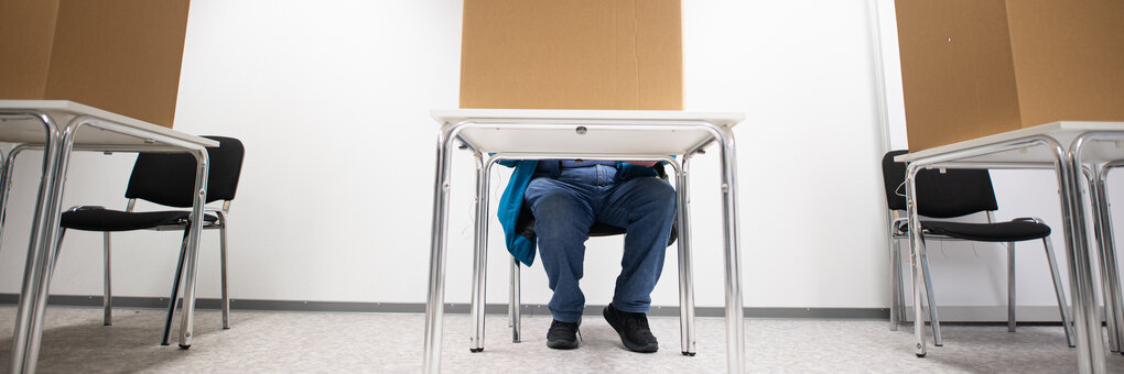 Ein Mann sitzt bei der Briefwahl in einer Wahlkabine in Hamburg