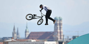 Schulze fliegt mit dem BMX vor dem Hintergrund der Frauentürme und hält sich nur am Lenker fest