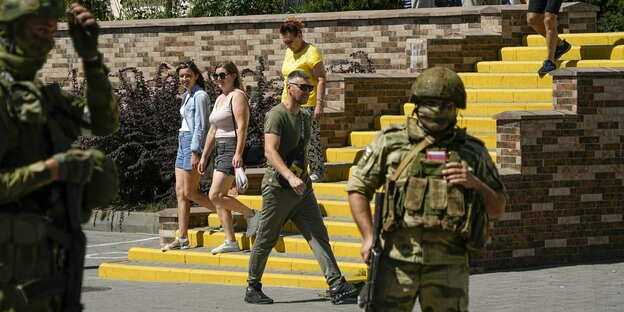 Zivilisten stehen mit russischen Soldaten an einer Promenade in Melitopol