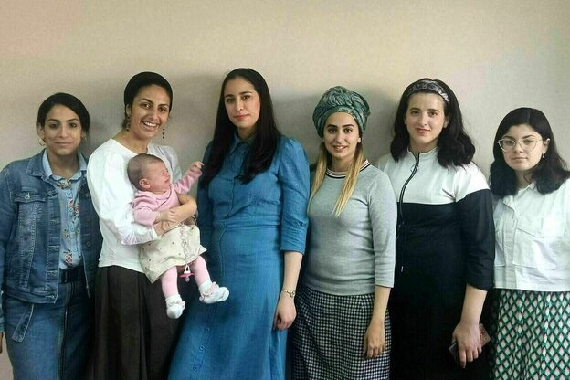 Eine Gruppe von Frauen steht vor einer Wand, eine Frau hält ein Baby im Arm Eine Gruppe von Frauen steht vor einer Wand, eine Frau hält ein Baby im Arm