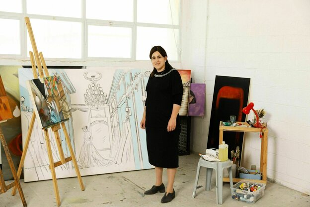 Eine Frau steht in einem Atelier neben einer Staffelei Eine Frau steht in einem Atelier neben einer Staffelei